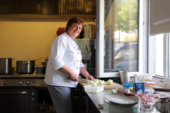 Fritz Reuter Pflegedienst GmbH Küchenchefin schneidet Gemüse in einer professionellen Küche.
