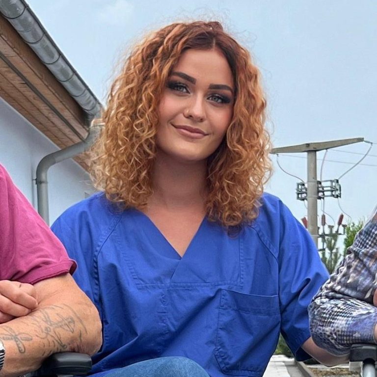 Nancy Schwindeler – Prokuristin Frau mit blonden Haaren und Brille, am Telefon, trägt T-Shirt mit Erdbeeren.